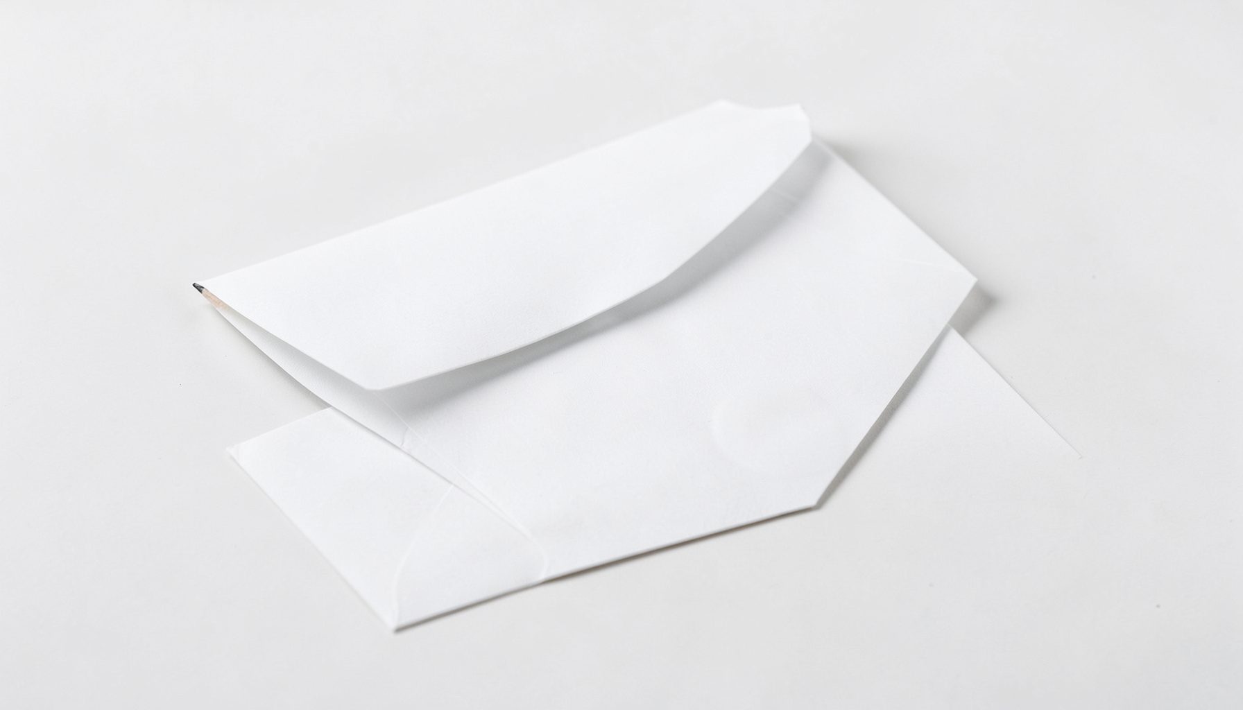 Enveloppe et stylo sur un fond clair, tons blancs et gris, ambiance professionnelle et épurée